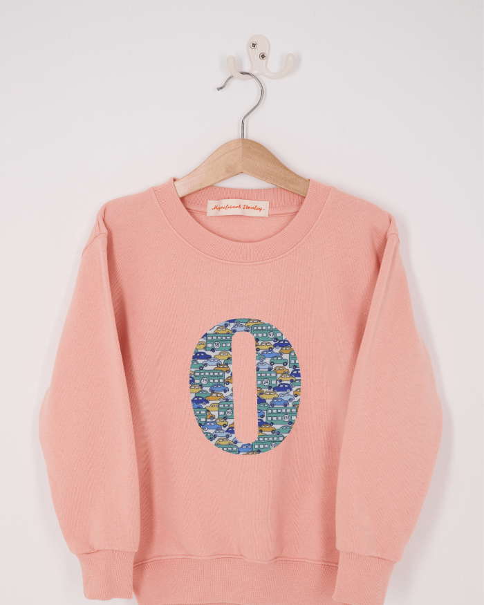 A pink personalised sweatshirt with an initial sewn on to the front. The initial is made from vintage car liberty print