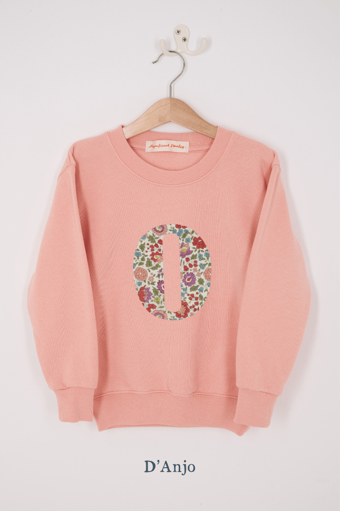 A pink personalised sweatshirt with an initial sewn on to the front. The initial is made from D'Anjo floral liberty print