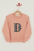 a personalised dusty pink sweatshirt with an initial on in Quey 2 Liberty print on the front.