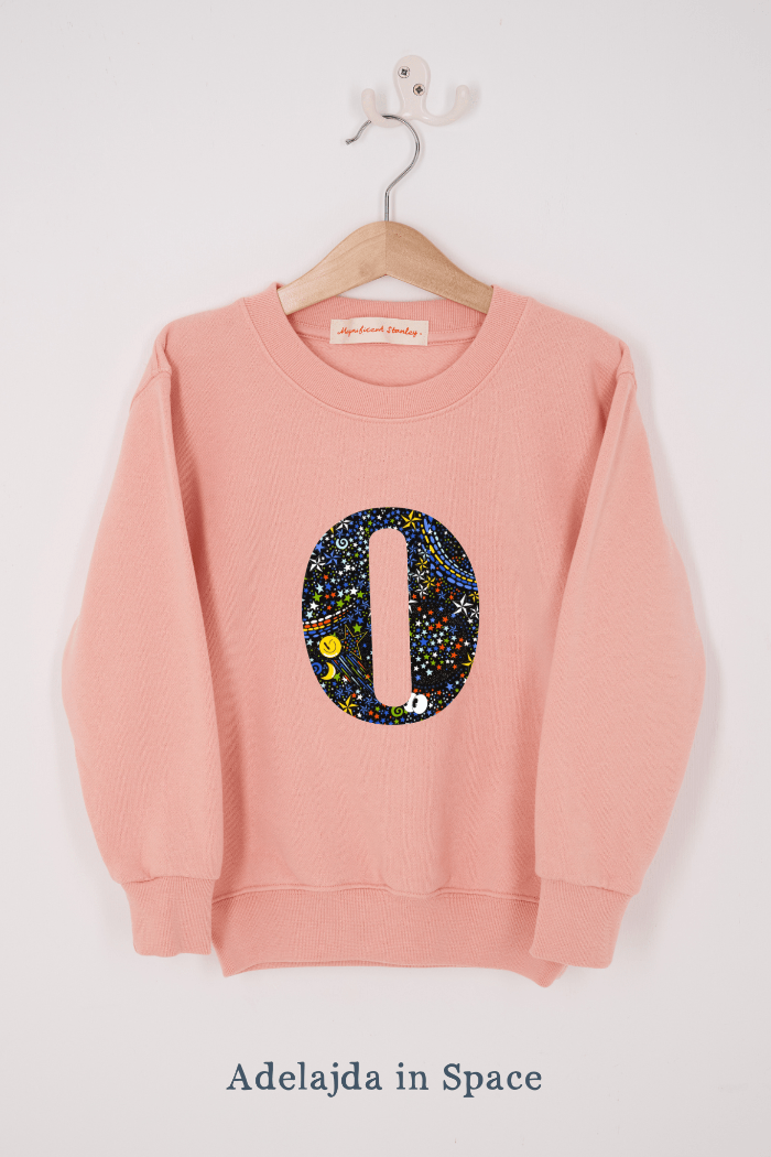 a personalised dusty pink sweatshirt with an initial on in Adelajda in Space Liberty print on the front.