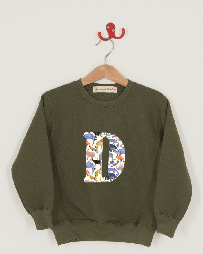 A khaki sweatshirt with an initial on the front. The initial is made from Queue for the Zoo Liberty print.