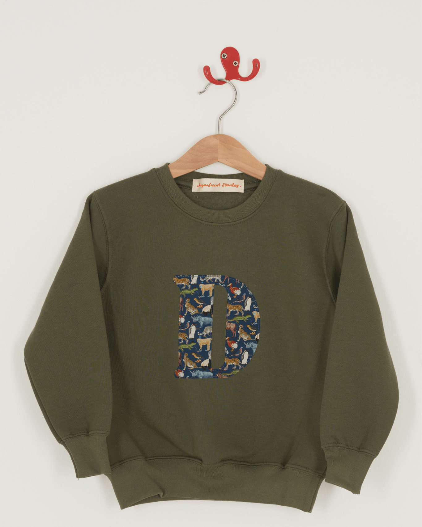 A khaki sweatshirt with an initial on the front. The initial is made from Liberty print featuring zoo animals.