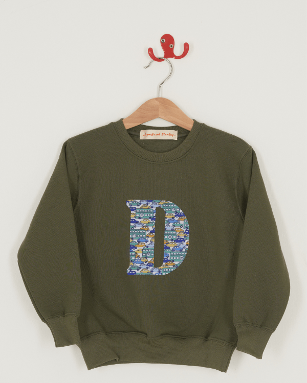 A khaki sweatshirt with an initial on the front. The initial is made from vintage cars Liberty print.