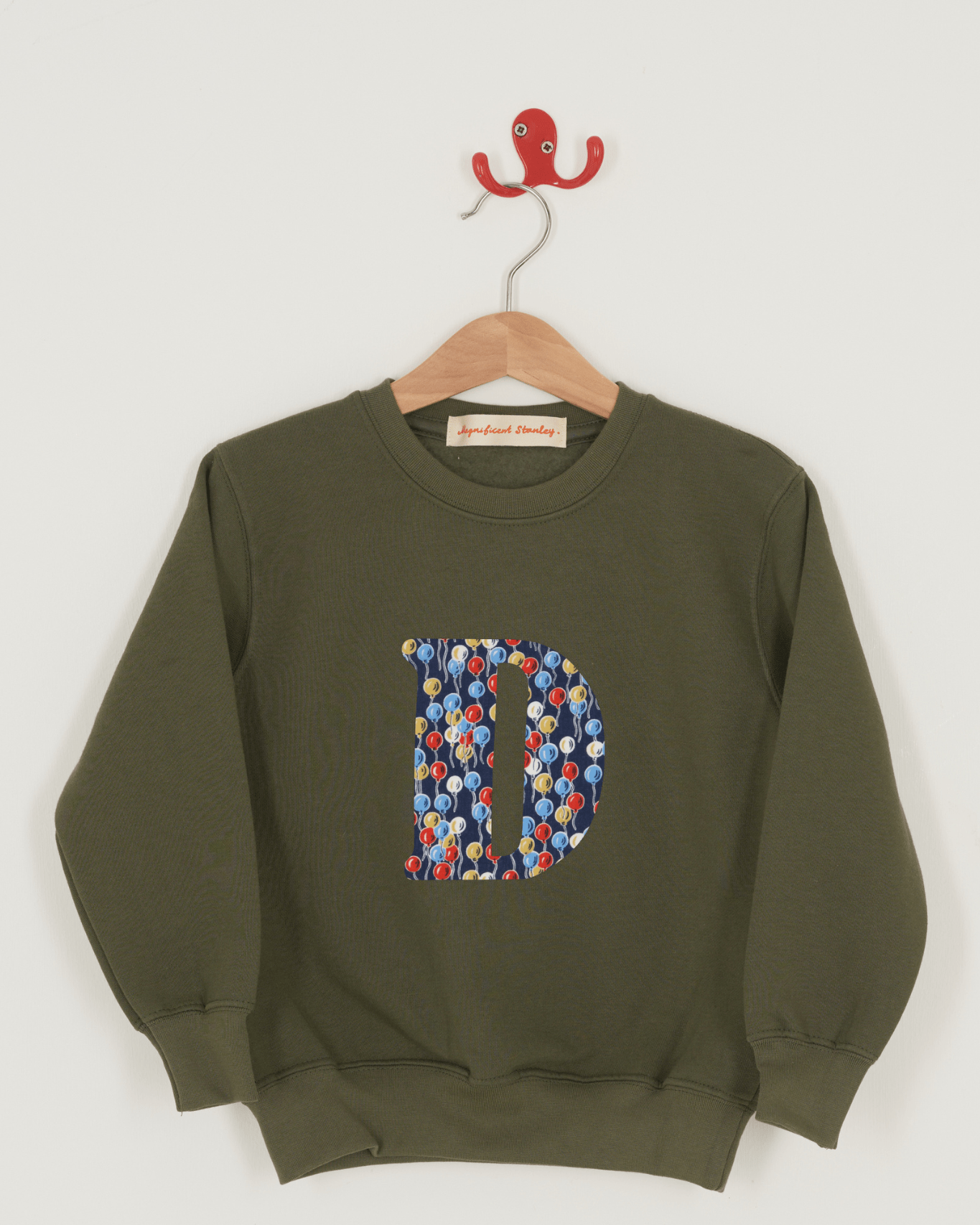 A khaki sweatshirt with an initial on the front. The initial is made from balloon Liberty print.