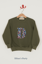 A khaki sweatshirt with an initial on the front. The initial is made from balloon Liberty print.