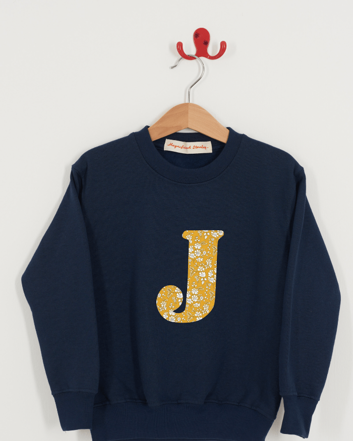 A personalised navy sweatshirt with an initial on in capel Liberty fabric.