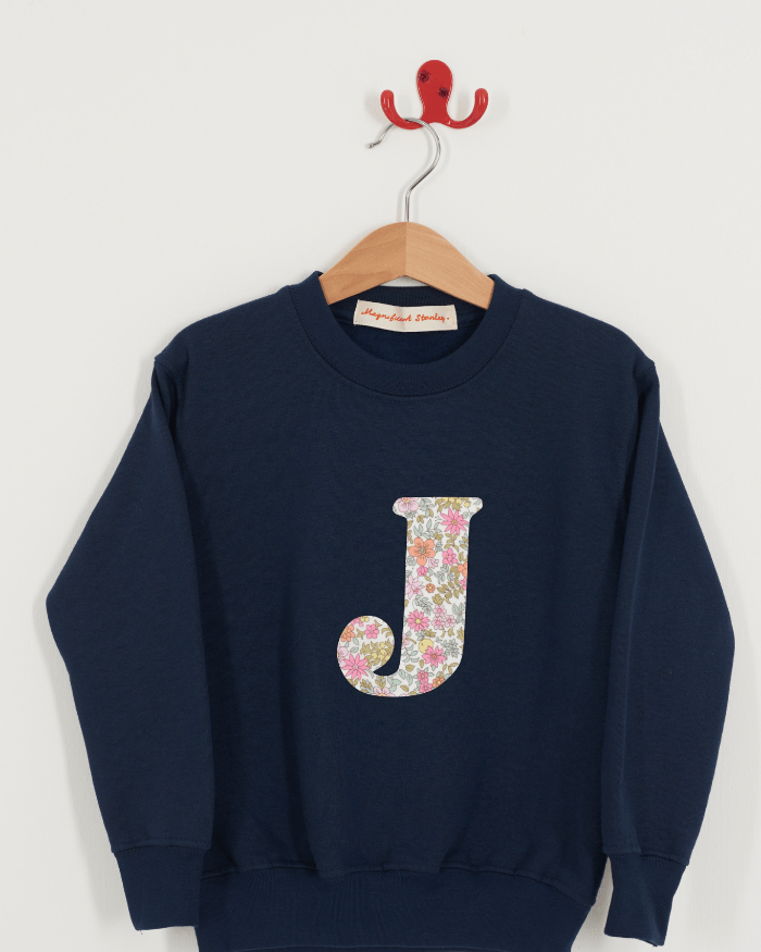 A personalised kids navy sweatshirt with an initial on in Floral Liberty fabric.
