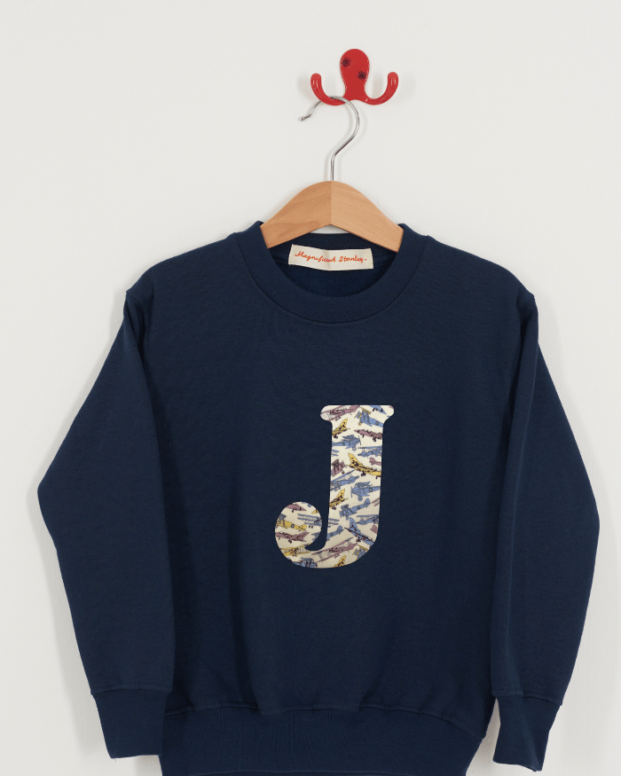A personalised navy sweatshirt with an initial on in Tom's Jet planes Liberty fabric.