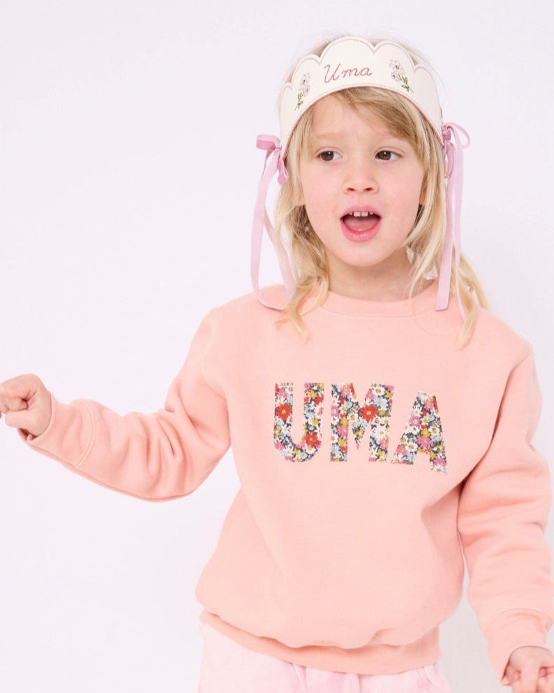 a 4 year old girl wearing a Magnificent Stanley Dusty Pink Sweatshirt  with her name sewn on in Libby floral Liberty Print