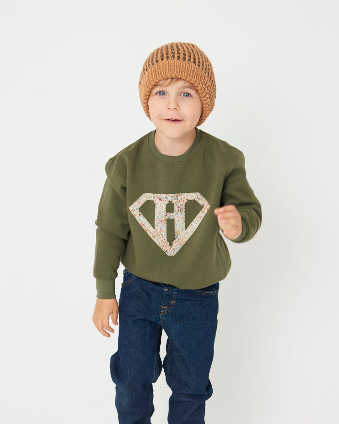 a happy kid in a Magnificent Stanley sweatshirt Superhero initial Khaki Sweatshirt in star Adelajda Liberty fabric