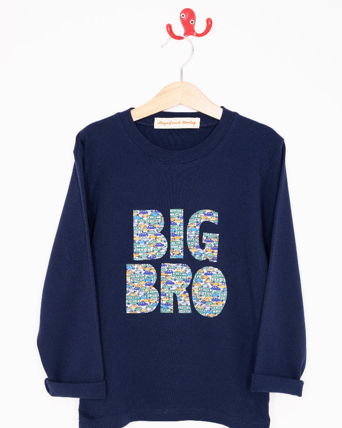 A navy t-shirt with BIG BRO sewn onto it in vintage liberty cars print hanging on a white wall