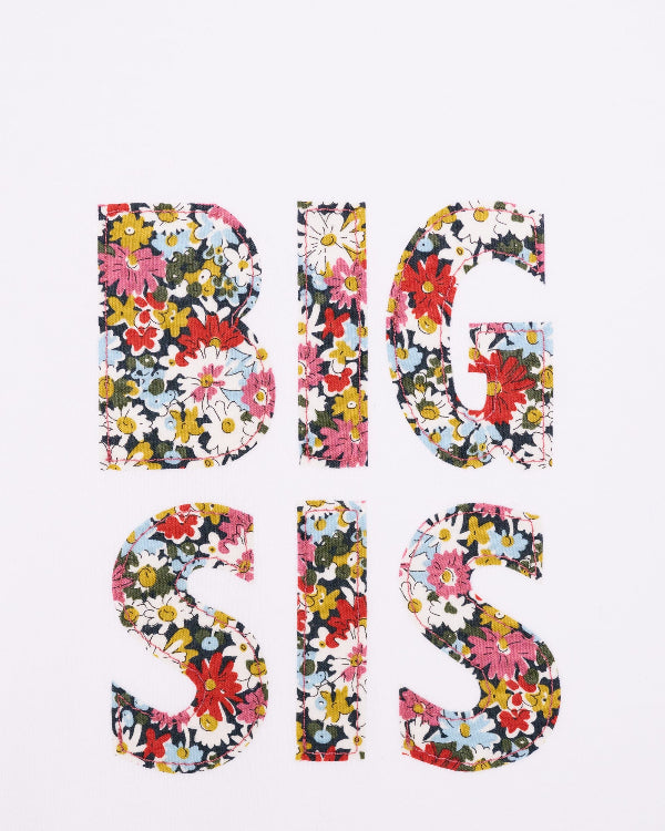 A close up of a white cotton t-shirt with BIG SIS in floral letters on the front. the letters are cut from Liberty print and appliquéd on.
