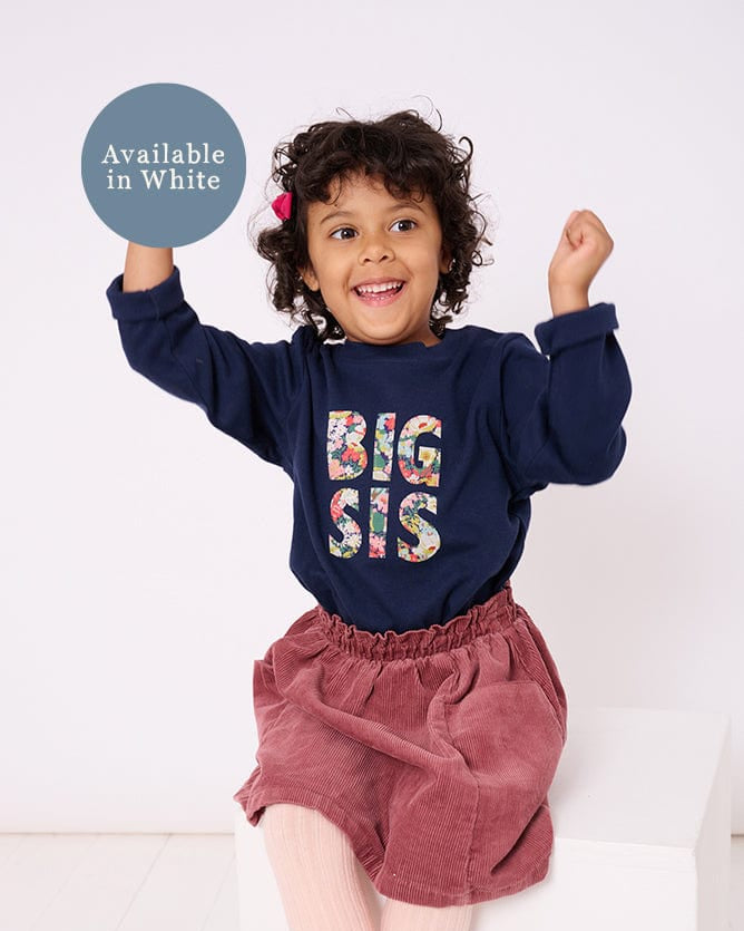5 year old girl who is a big sister wearing a navy cotton t-shirt with BIG SIS in floral letters on the front. the letters are cut from Liberty print and appliquéd on.