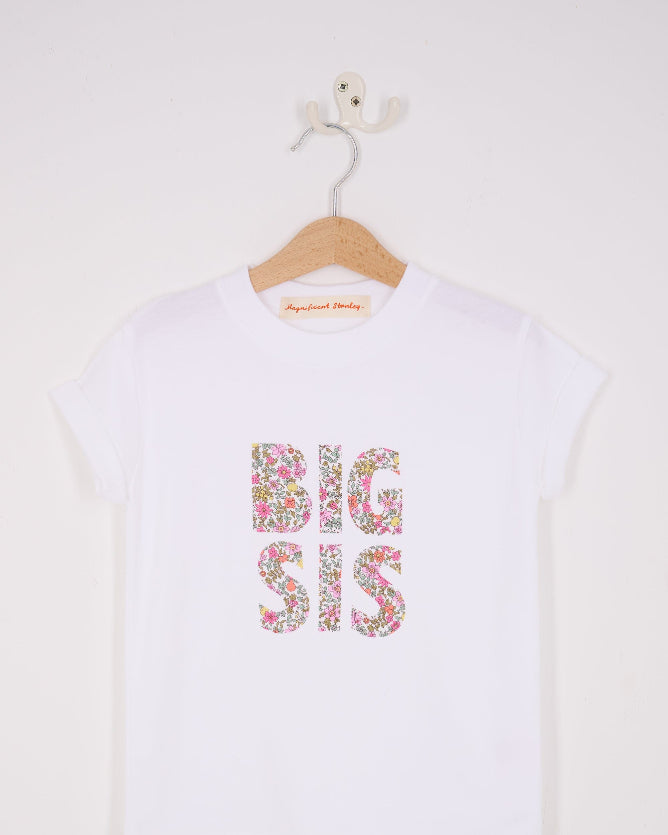 A white cotton t-shirt with BIG SIS in floral letters on the front. the letters are cut from Liberty print and appliquéd on.