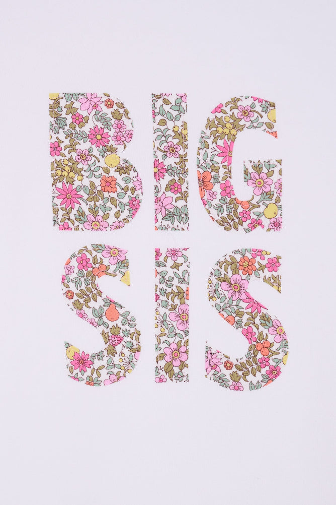 A close up pf a white cotton t-shirt with BIG SIS in floral letters on the front. the letters are cut from Liberty print and appliquéd on.