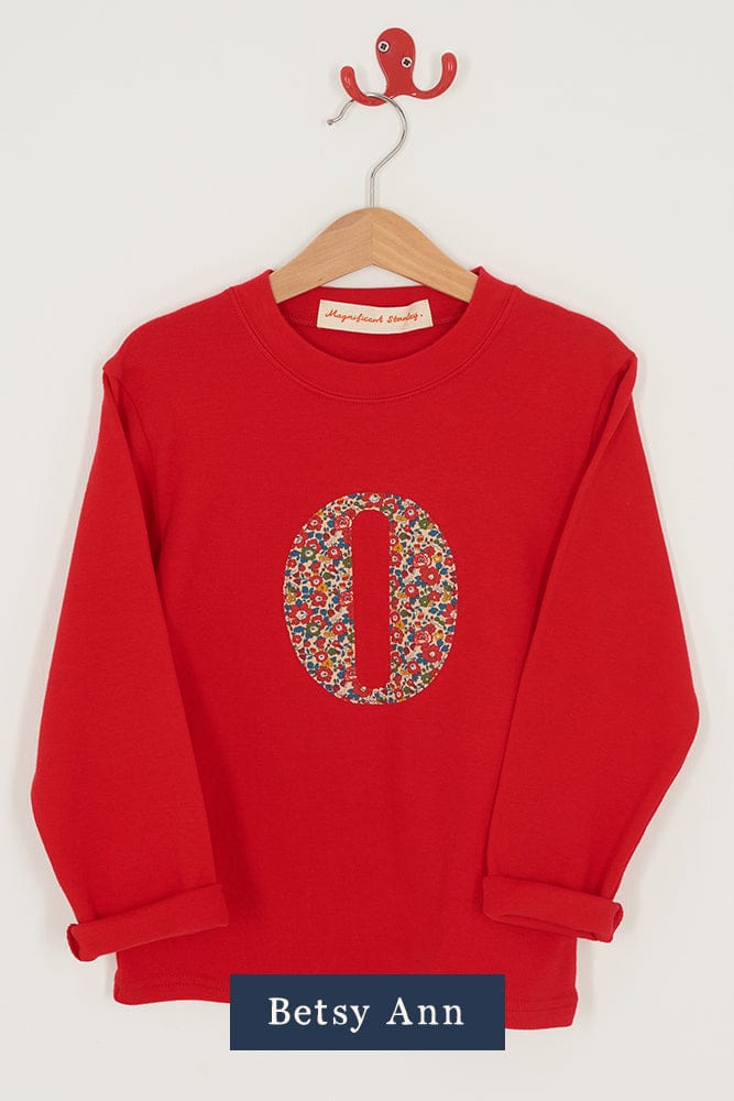 A red personalised t-shirt with a liberty floral letter O appliquéd on the front.