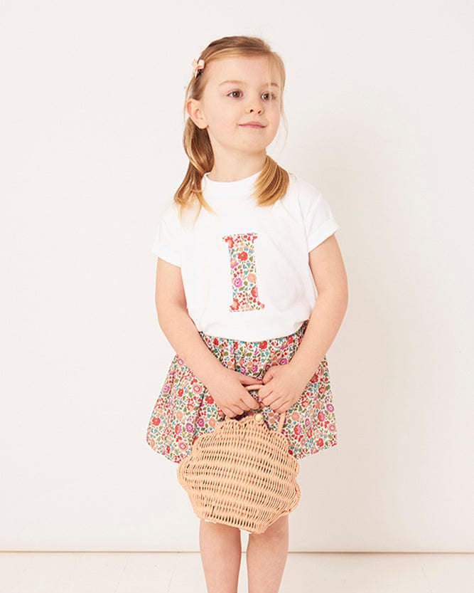 A 3 year old girl wearing a personalised white cotton t-shirt with her initial on in D'Anjo floral Liberty fabric.
