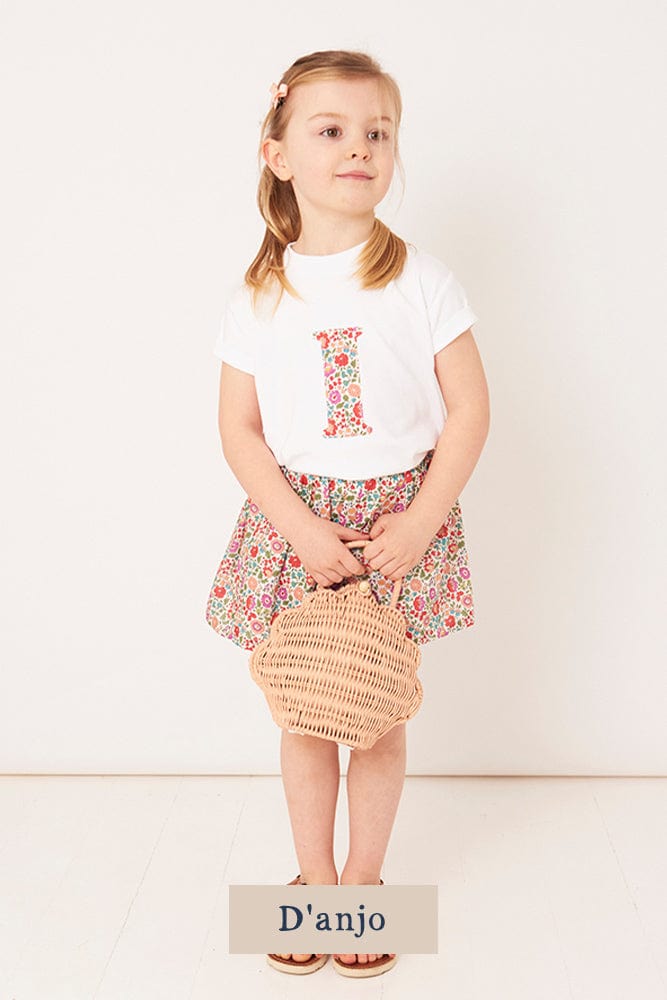 A 3 year old girl wearing a personalised white cotton t-shirt with her initial on in D'Anjo floral Liberty fabric.