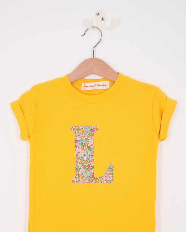 a personalised kids yellow t-shirt with an initial cut from poppy forest liberty floral print on the front