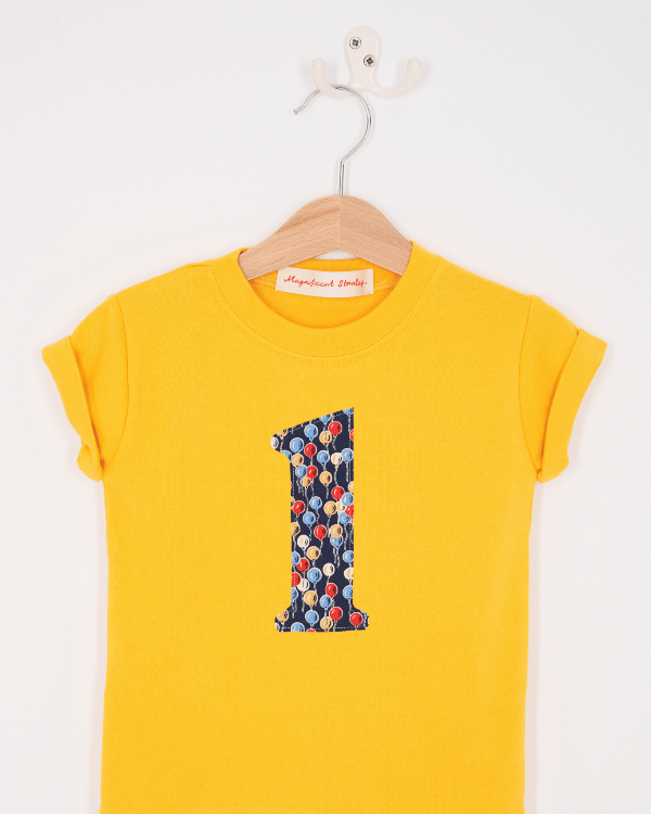 a yellow birthday t-shirt with a number 1 cut from ethan's party balloon liberty floral print on the front.