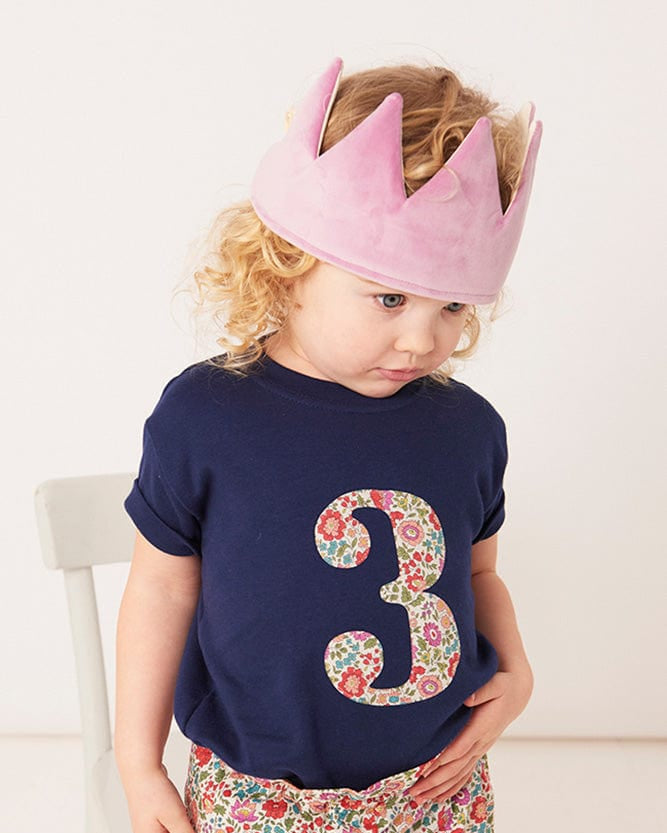 a 3 year old girl wearing a white birthday t-shirt with a number 3 cut from liberty floral print on the front