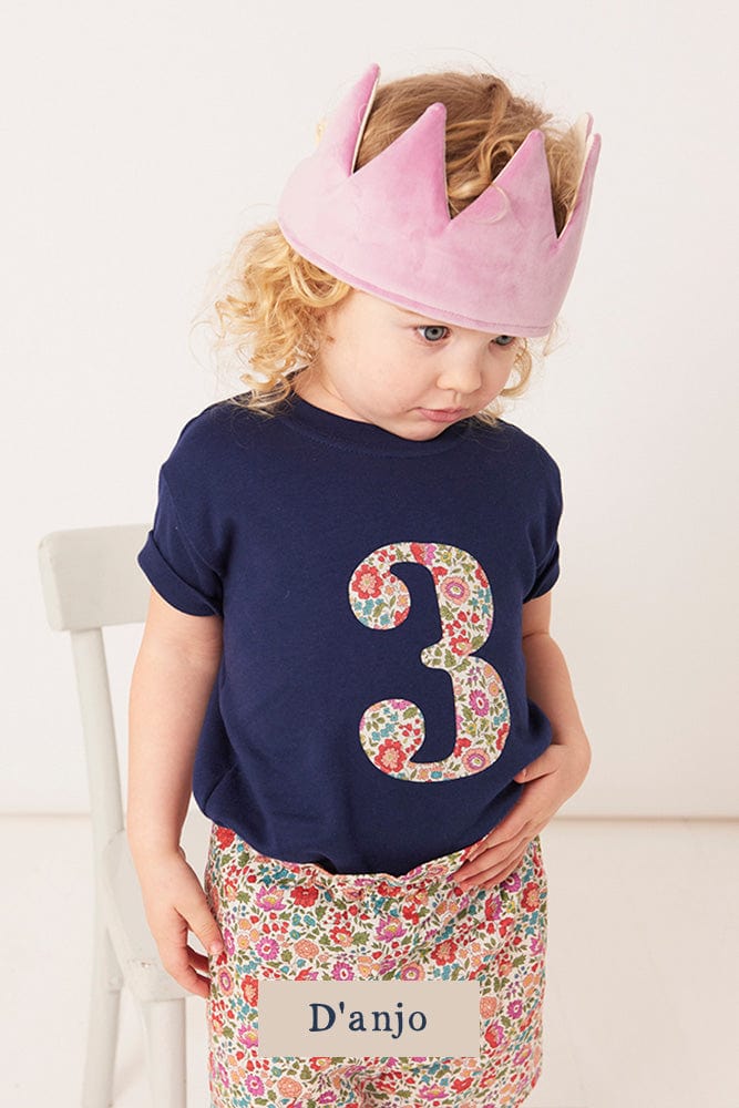 a 3 year old girl wearing a white birthday t-shirt with a number 3 cut from liberty floral print on the front