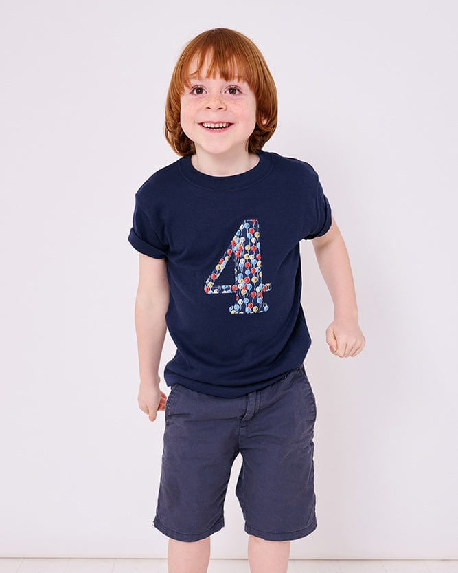 a 4 year old boy wearing a navy birthday t-shirt with a number 4 cut from ethan's party balloon liberty print on the front