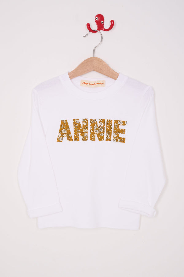 a white personalised t-shirt with a name on the front cut from Capel Mustard liberty print.
