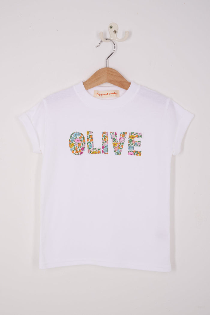 a white personalised t-shirt with her name on the front cut from Poppy Forest liberty print.