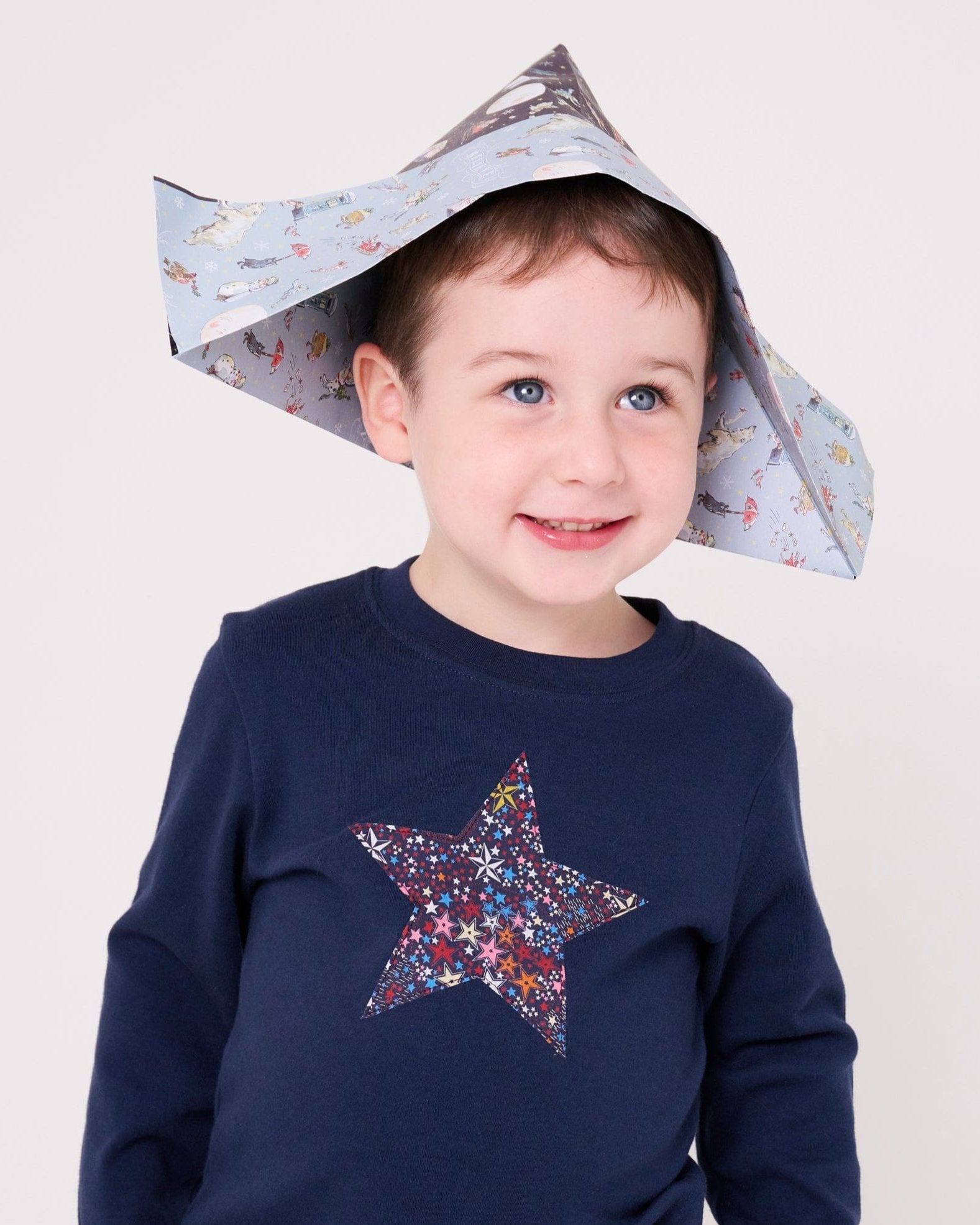 a 5 year old boy wearing a navy long sleeve christmas t-shirt with a festive star on the front made from Liberty Adelajda's Wish star print on the front.