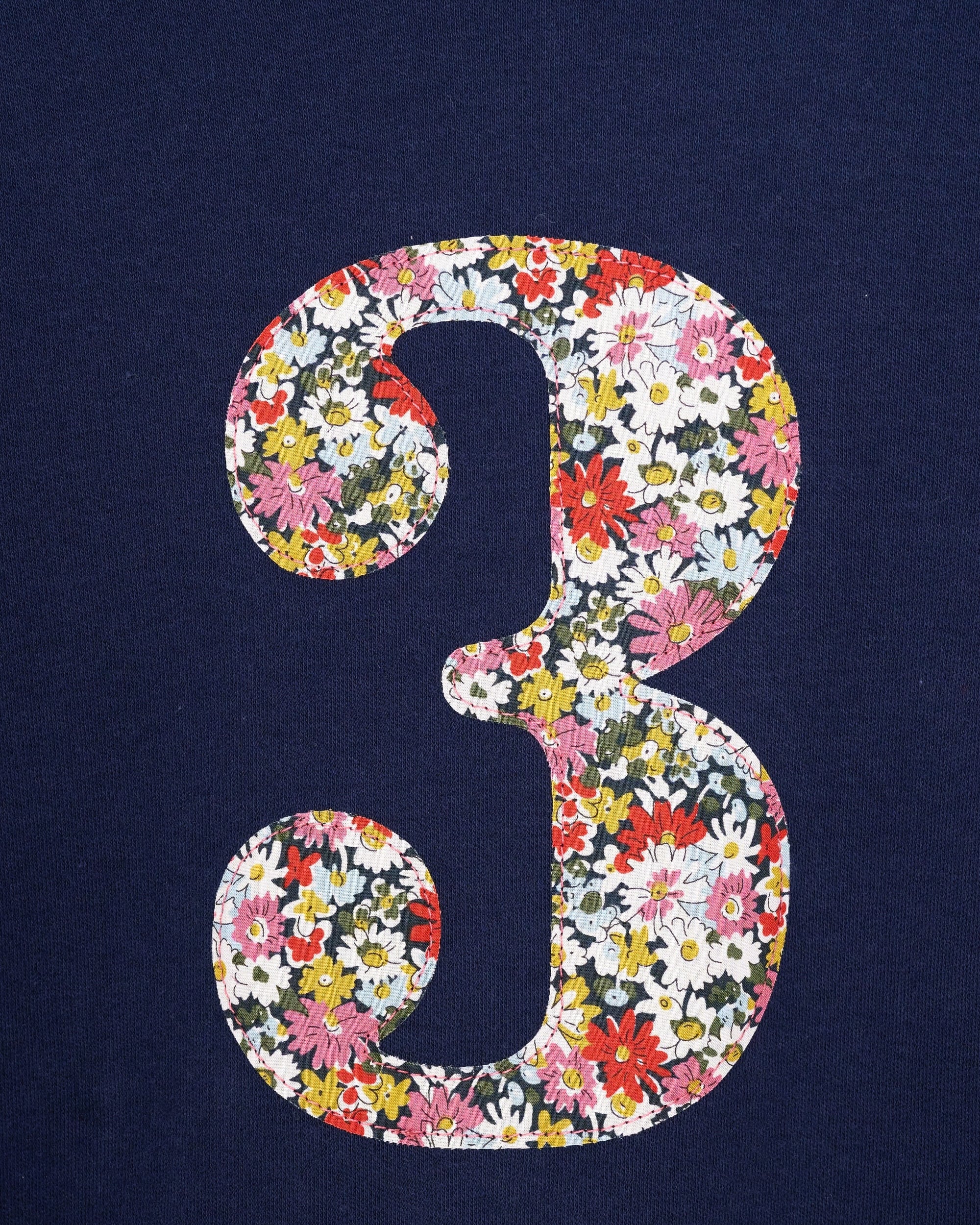 A long sleeve navy t-shirt with a floral liberty number 3 on the front.