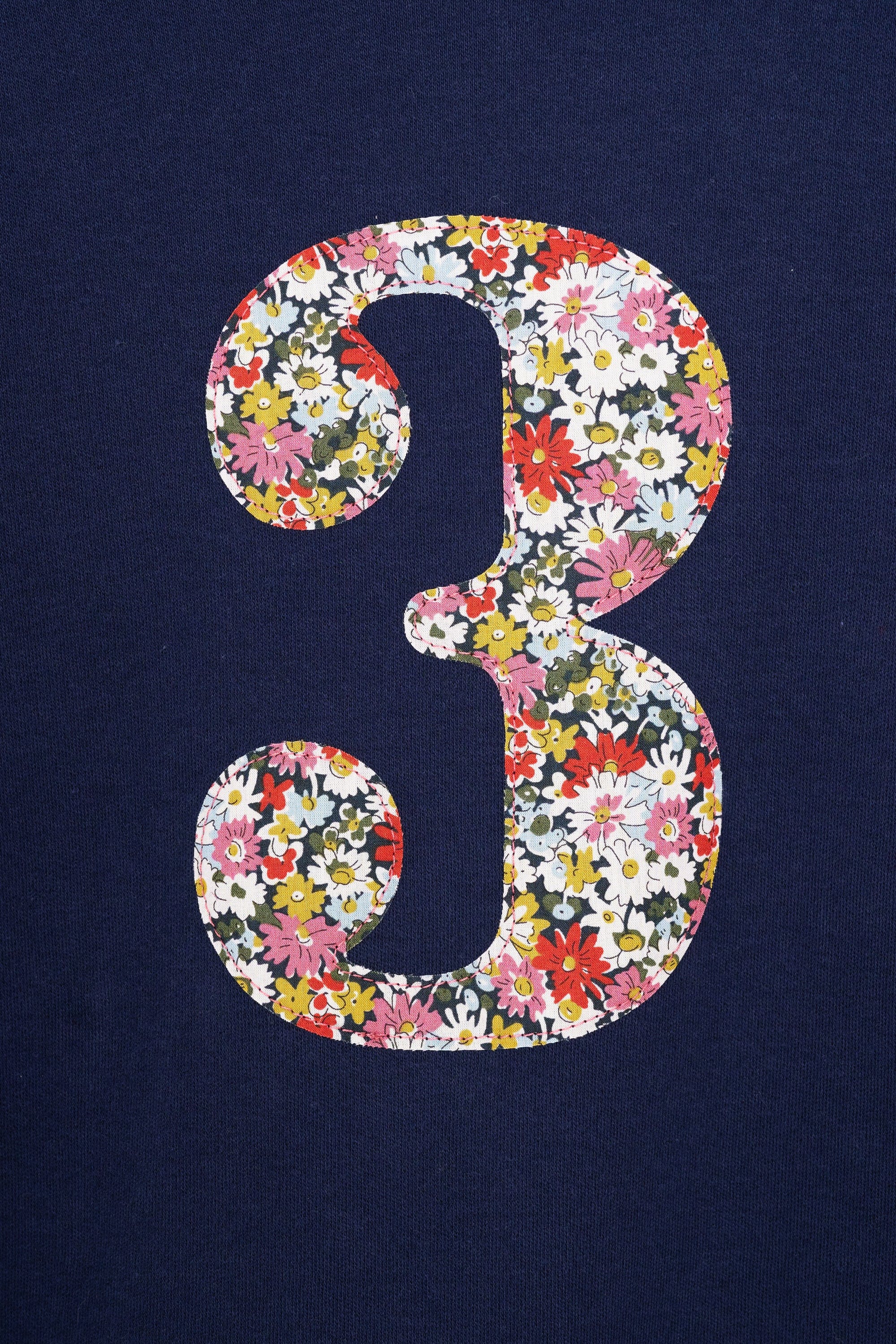 A long sleeve navy t-shirt with a floral liberty number 3 on the front.