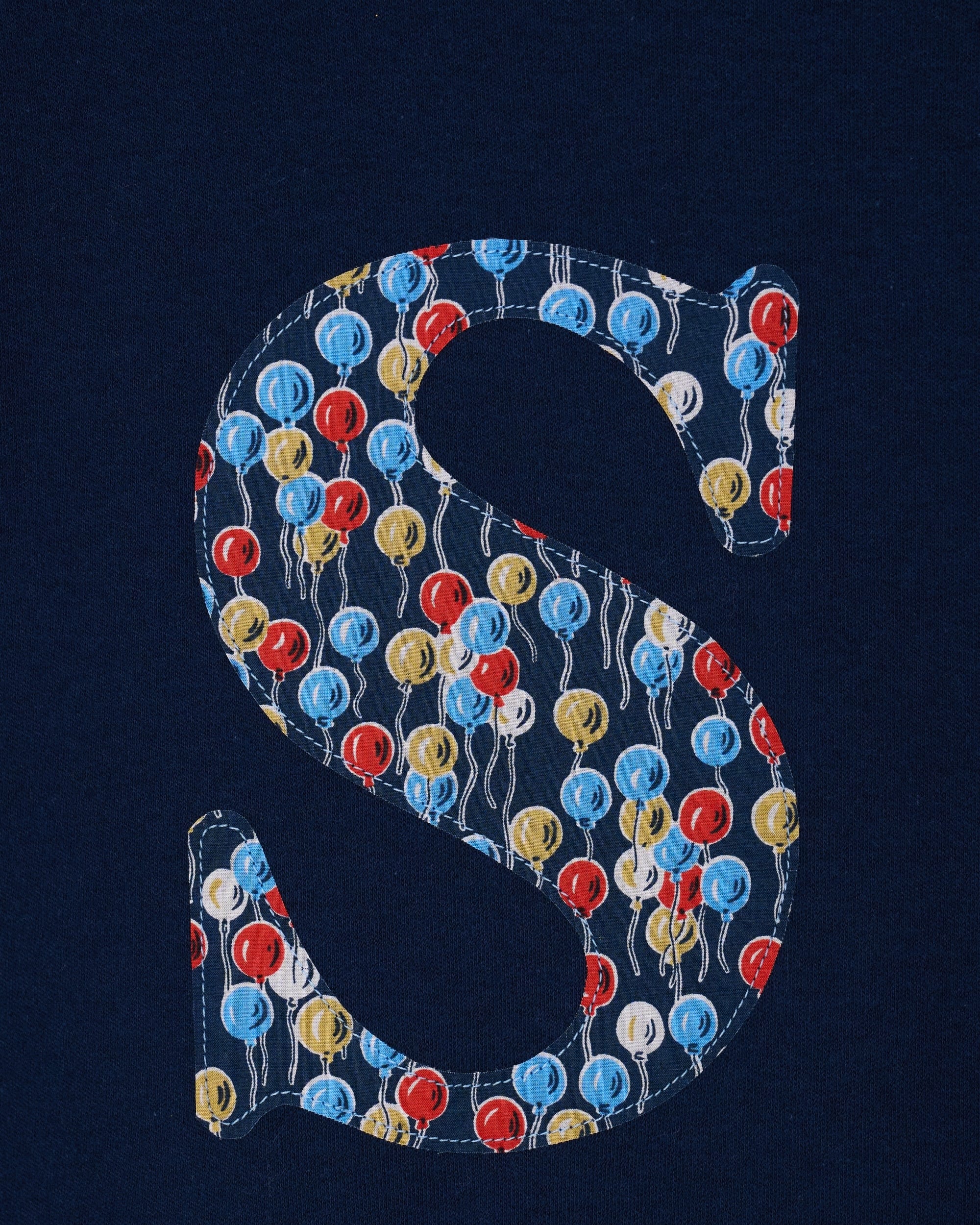 A close up of a navy cotton personalised t-shirt with an initial in Liberty balloon print.