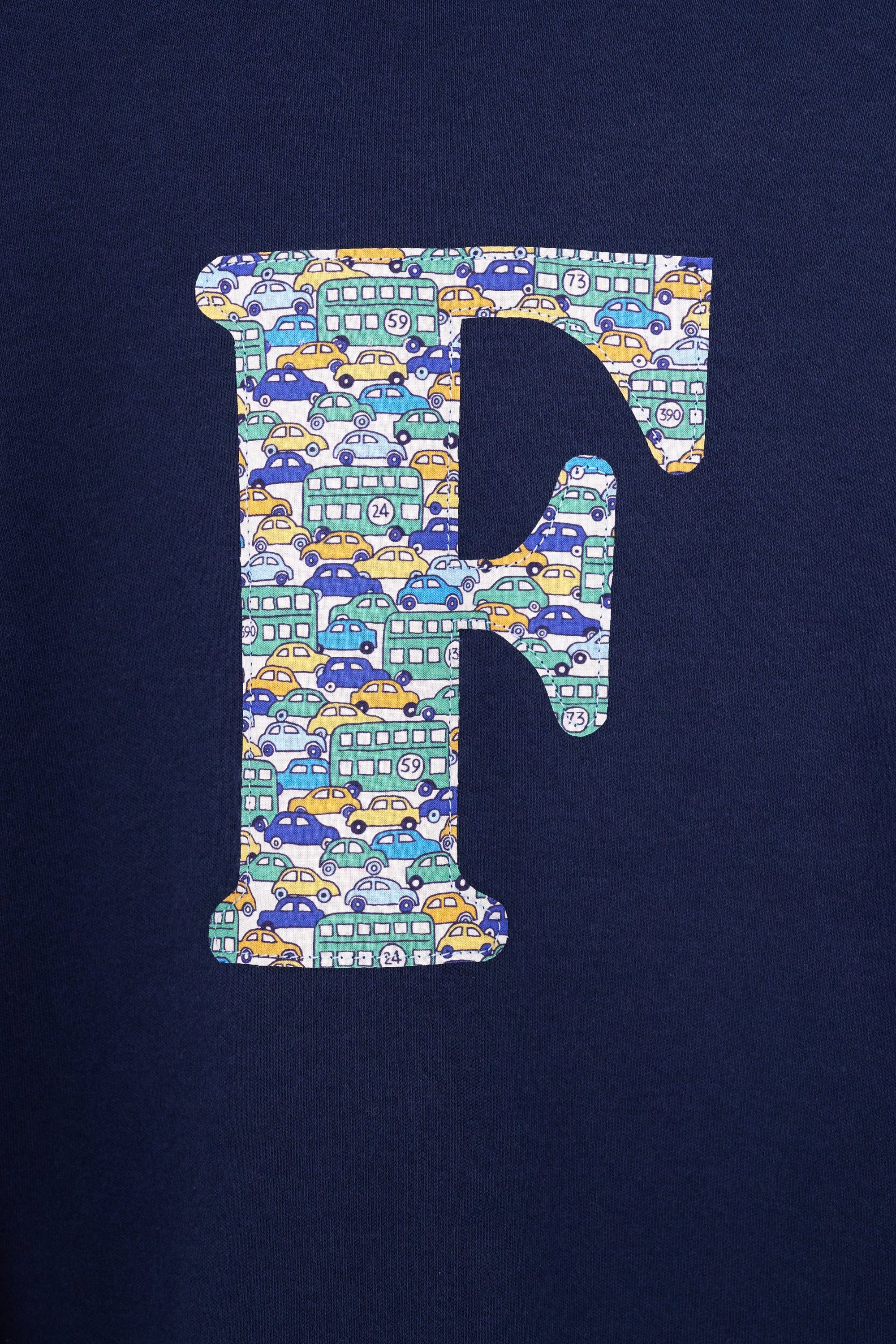 A case up of a personalised cotton long sleeve navy t-shirt with an initial on the front made from Liberty cars print fabric.