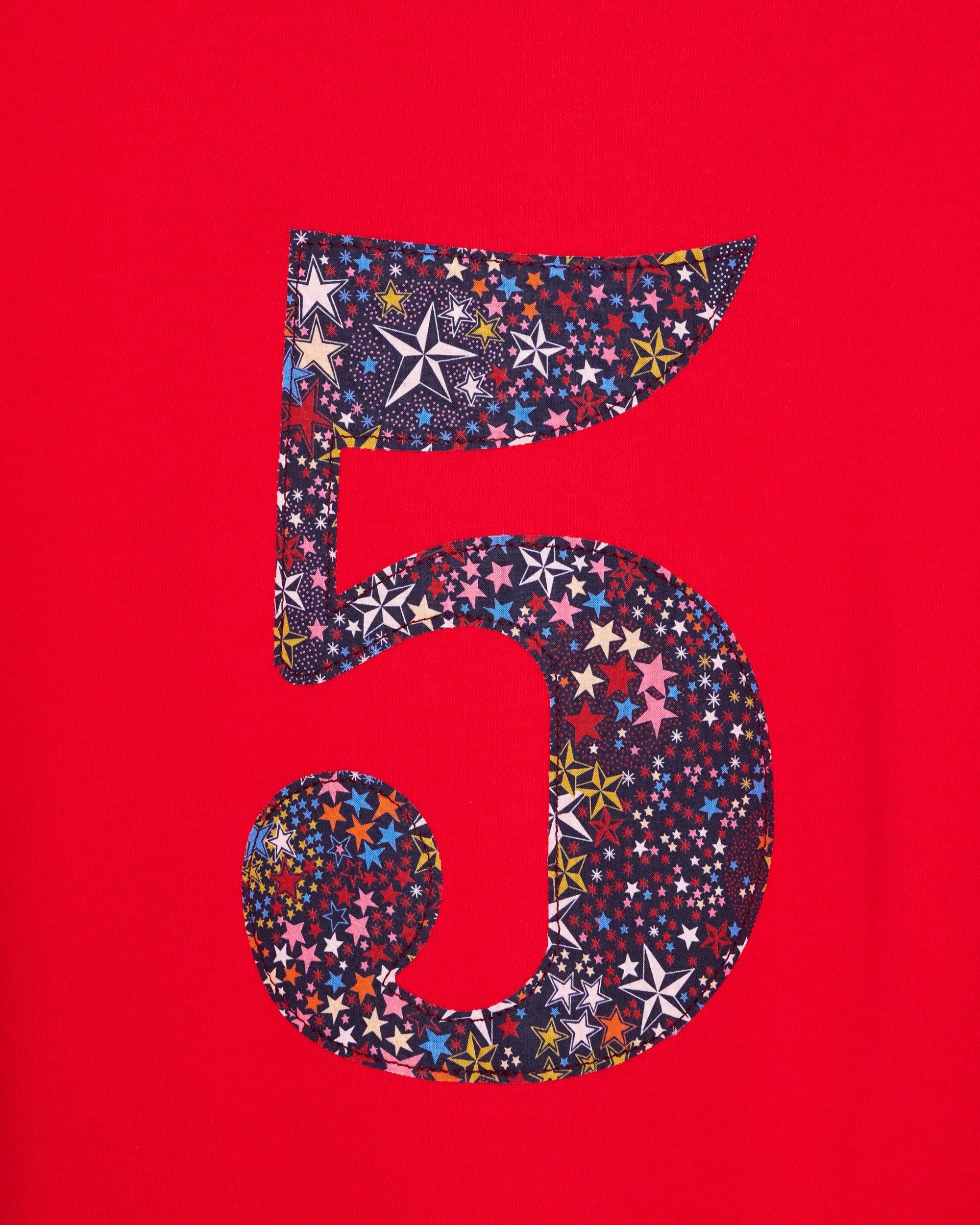 A close up of the appliqué on a red birthday t-shirt with the number 5 sewn onto it in Liberty Adelajda star print fabric.