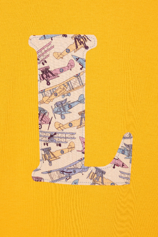 A close up of the stitching on a personalised yellow T-Shirt in with his initial in Tom's Jet Liberty Print