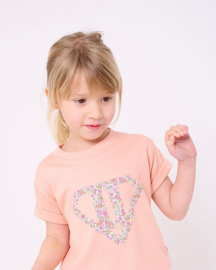 A little girl wearing a Superhero Pink T-Shirt in with her initial in Fruit Punch Liberty Print