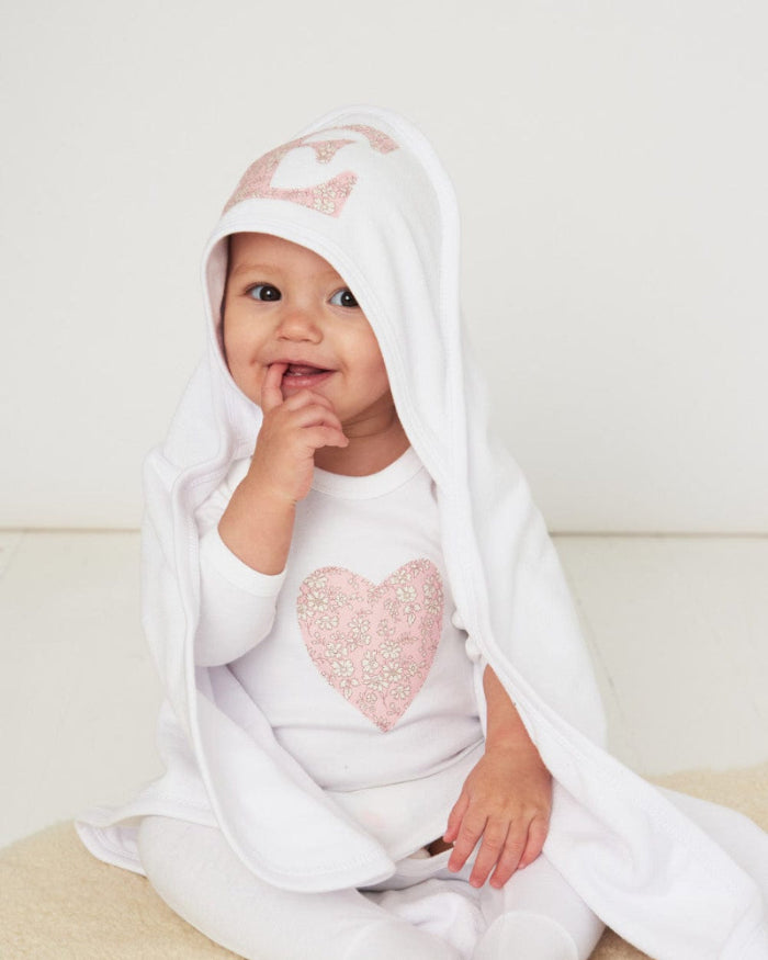 A little baby wearing a soft cotton hooded baby towel with a heart sewn on the hood in capel liberty print