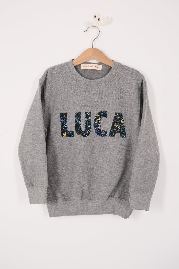 a grey sweatshirt with 'LUCA' in colourful letters in space liberty print.