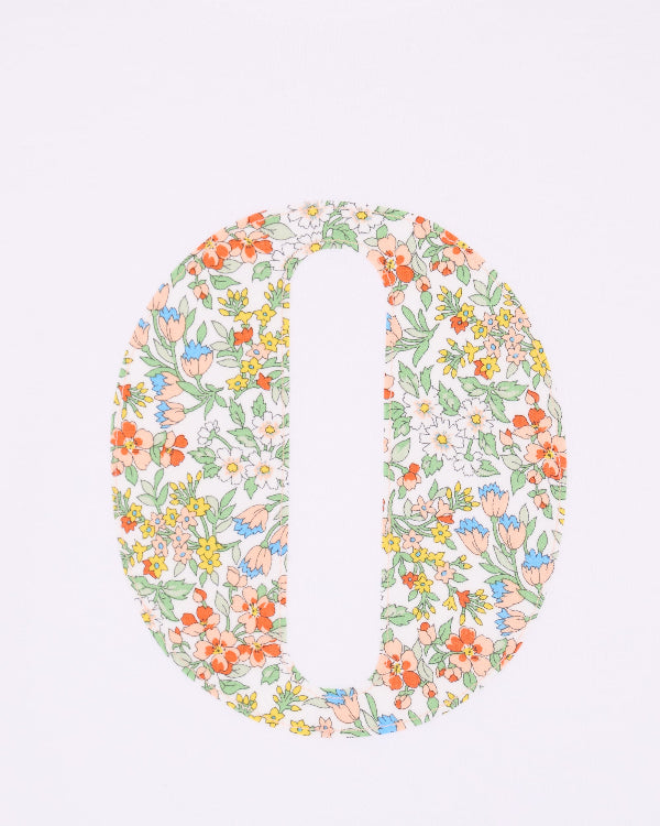 A close up of the stitching on a summery personalised white cotton t-shirt with an initial cut from Nazanin floral liberty fabric.