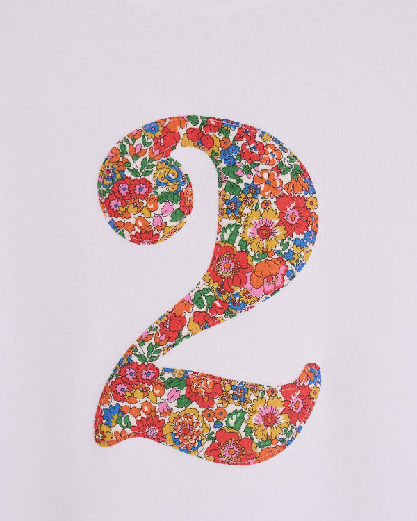 A close up of the stitching on a white cotton birthday t-shirt with the number 2 sewn on the front cut from liberty Nell Annie and May fabric