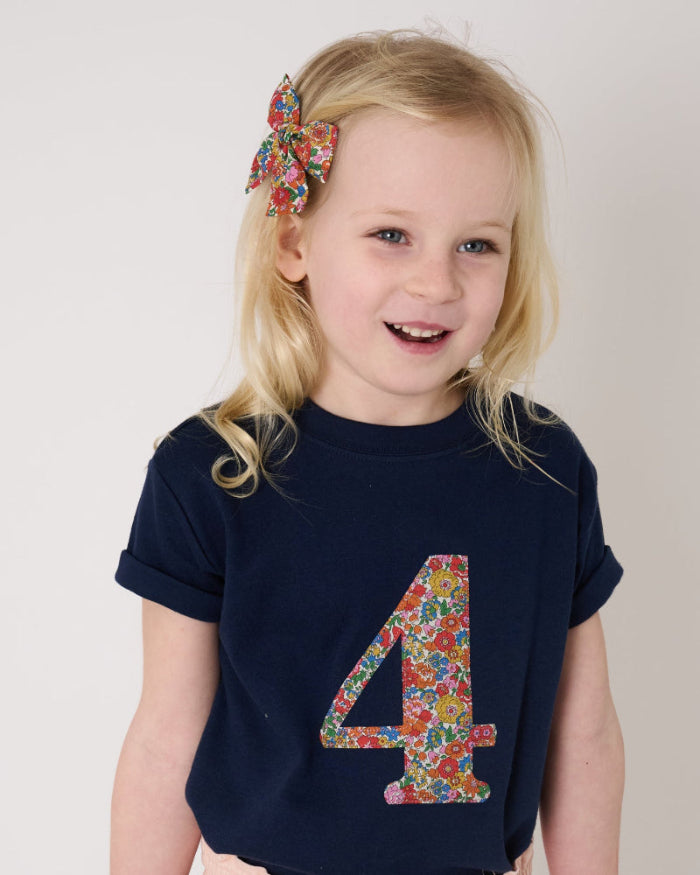 a 4 year old birthday girl wearing a navy cotton t-shirt with the number 4 sewn on the front cut from liberty floral Nell Annie and May print.