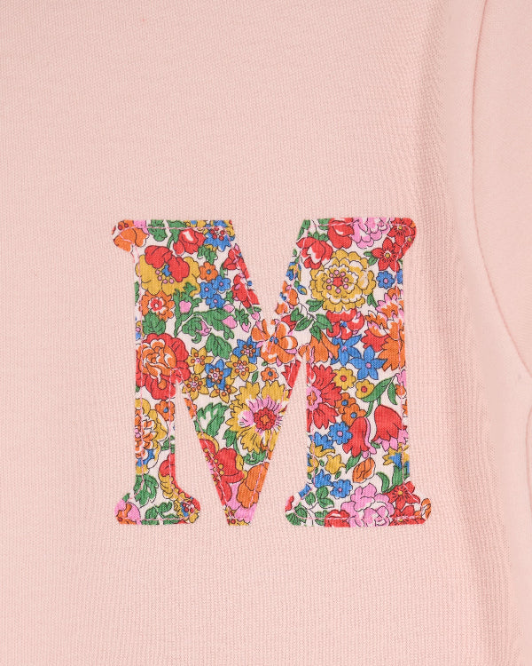 a pale pink t-shirt with a Liberty Nell Annie and May floral small initial on the front, a close up of the stitching