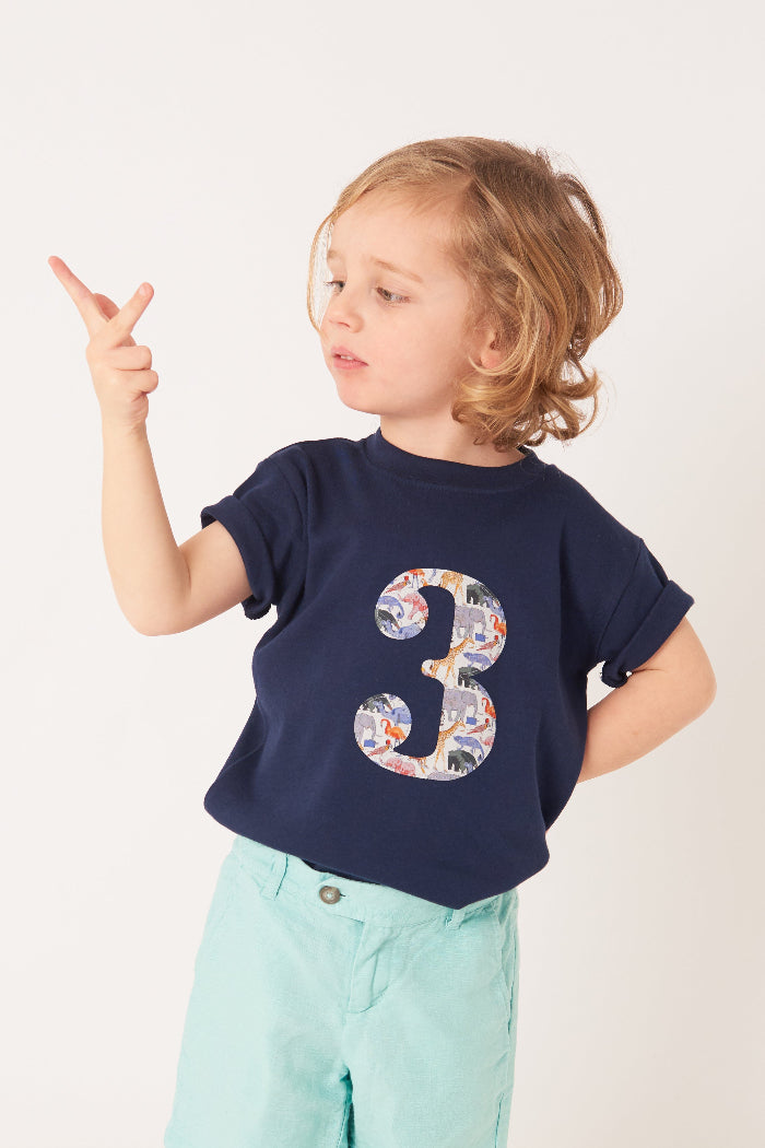 a 3 year old boy wearing a navy cotton t-shirt with the number 3 on the front cut from Queue for the Zoo liberty animal print