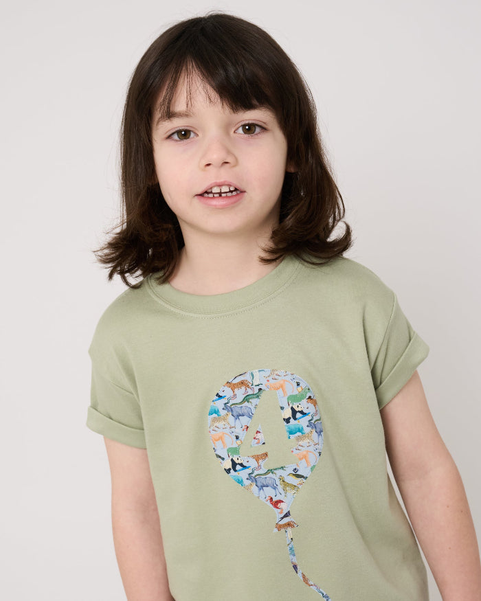 Child wearing a sage green t-shirt with a colourful number balloon design made from animal liberty print on a white background