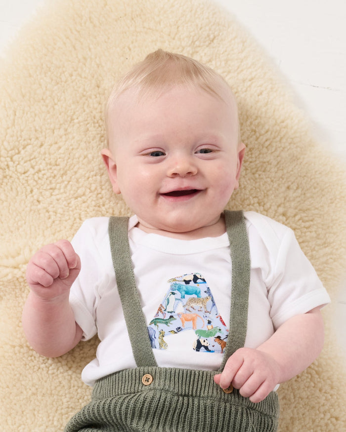 a smiling baby wearing a personalised baby bodysuit made from Liberty zoo animal print Quey 2
