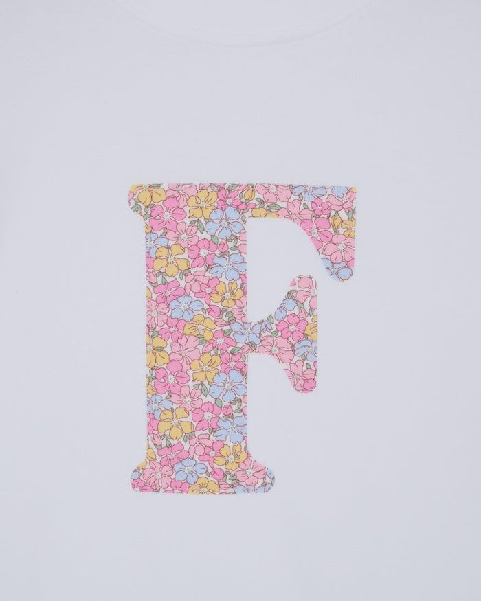a personalised kids white cotton t-shirt with an initial cut from sadie rose liberty floral print on the front. close up of the appliqué stitching.