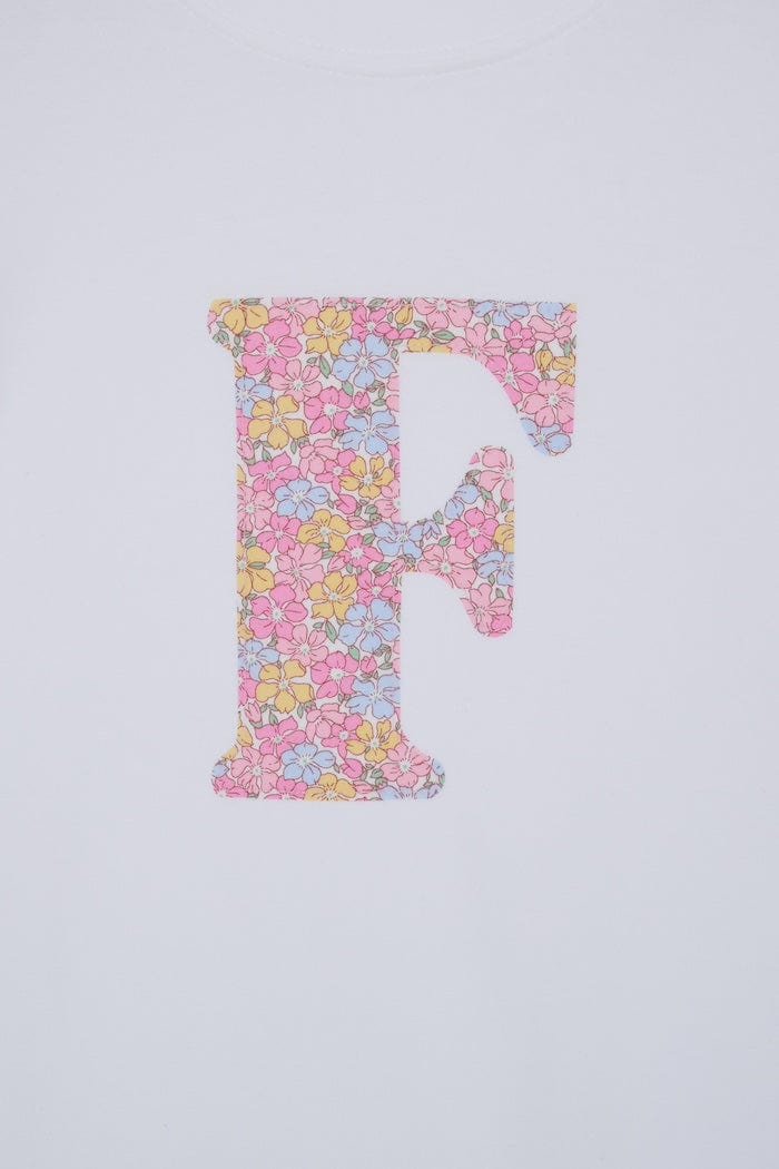 a personalised kids white cotton t-shirt with an initial cut from sadie rose liberty floral print on the front. close up of the appliqué stitching.