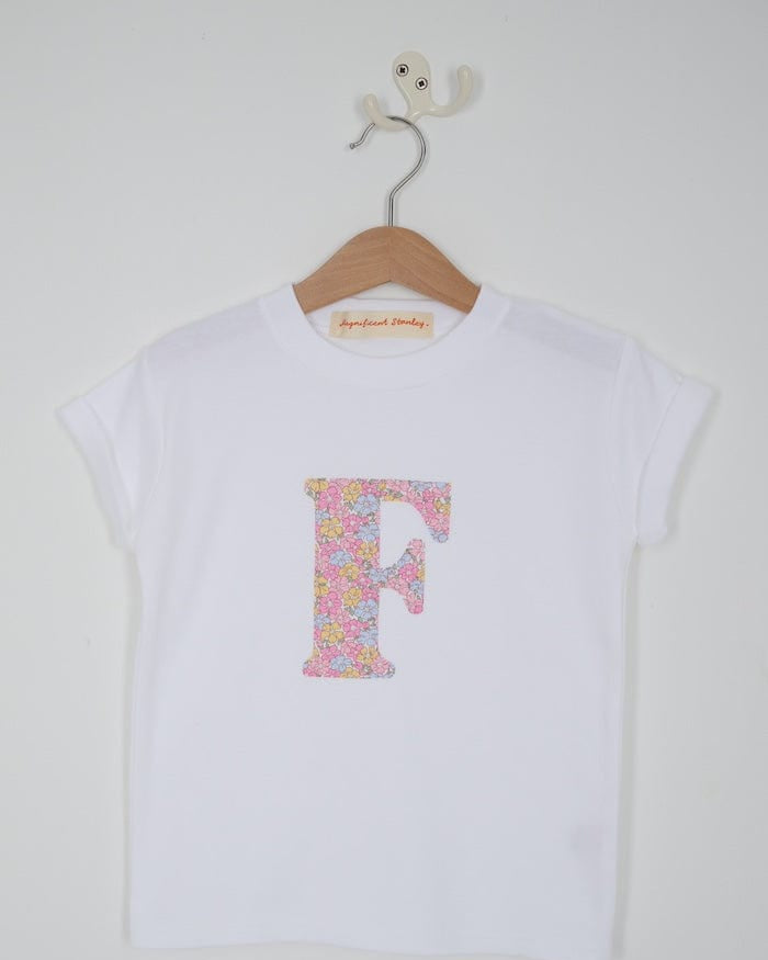 a personalised kids white cotton t-shirt with an initial cut from sadie rose liberty floral print on the front. close up of the appliqué stitching.
