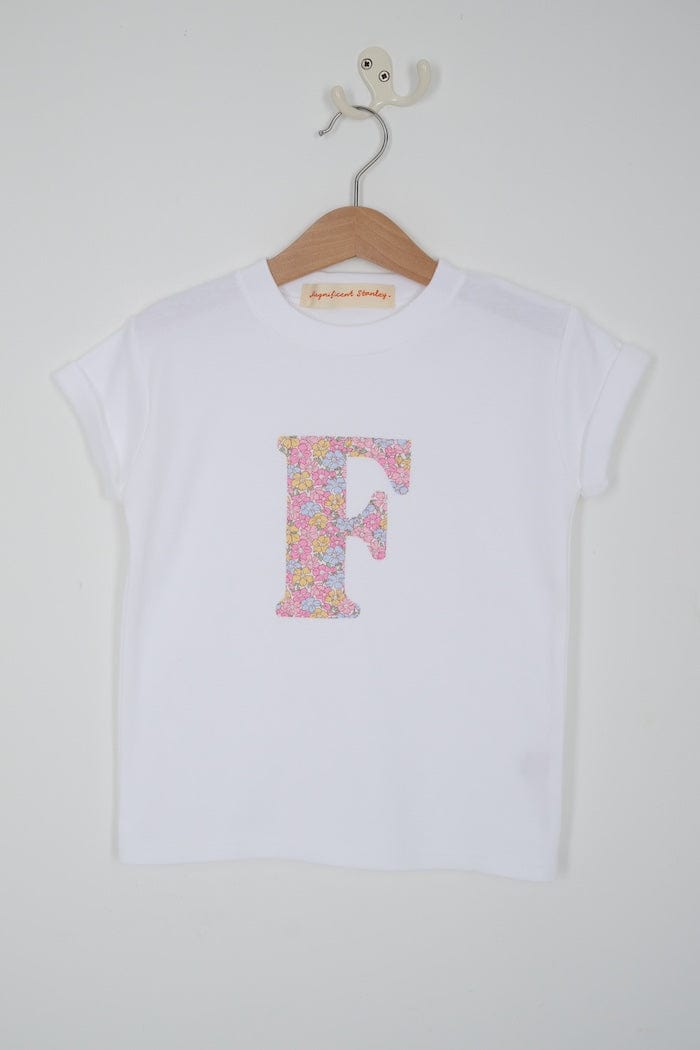 a personalised kids white cotton t-shirt with an initial cut from sadie rose liberty floral print on the front. close up of the appliqué stitching.